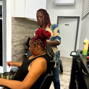 Professional stylist braiding a woman’s hair in a modern salon, showcasing women’s braiding and hair styling services.
